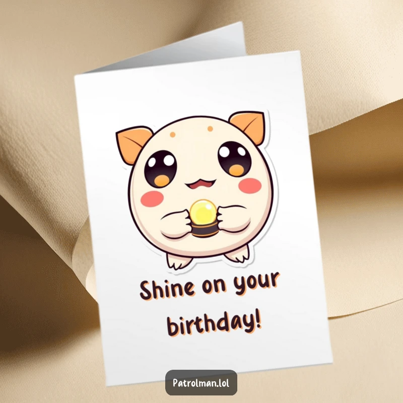 Free Printable Birthday Card: Round creature with wide eyes holds a small, glowing beacon, radiating hope.